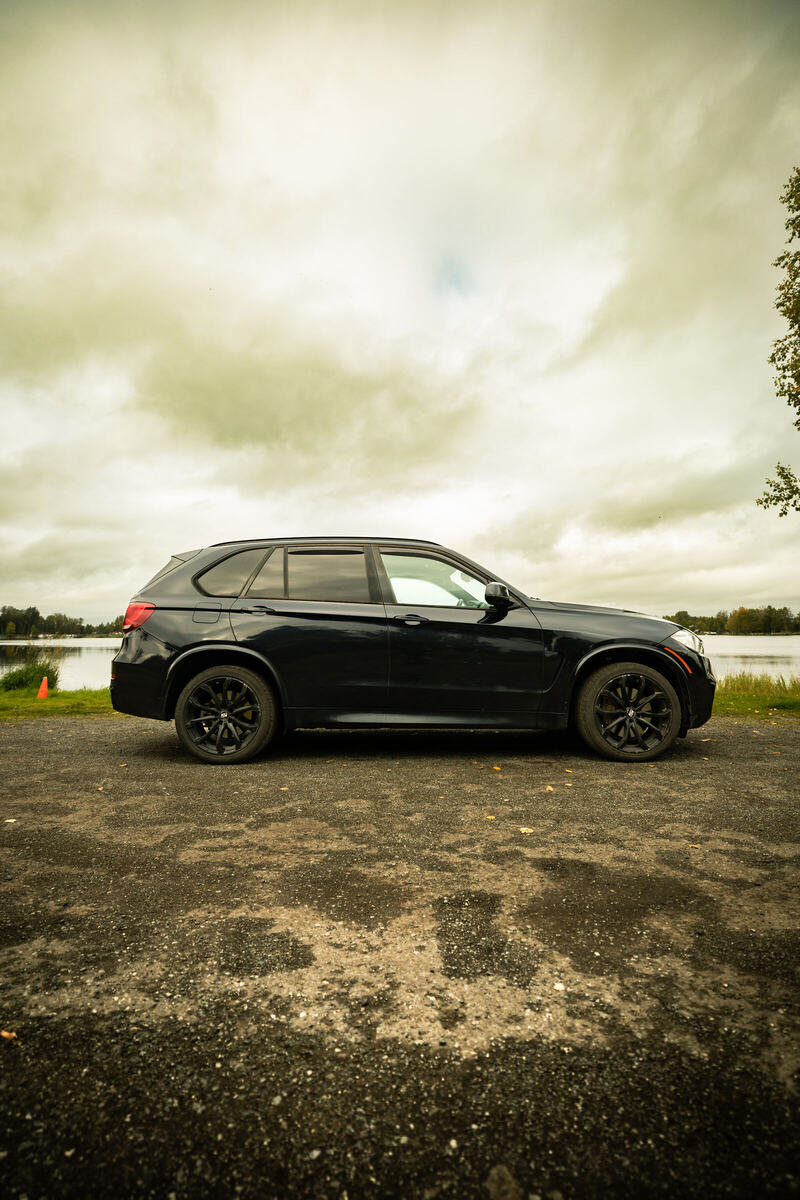 Black BMW X5 in profile with the lake behind