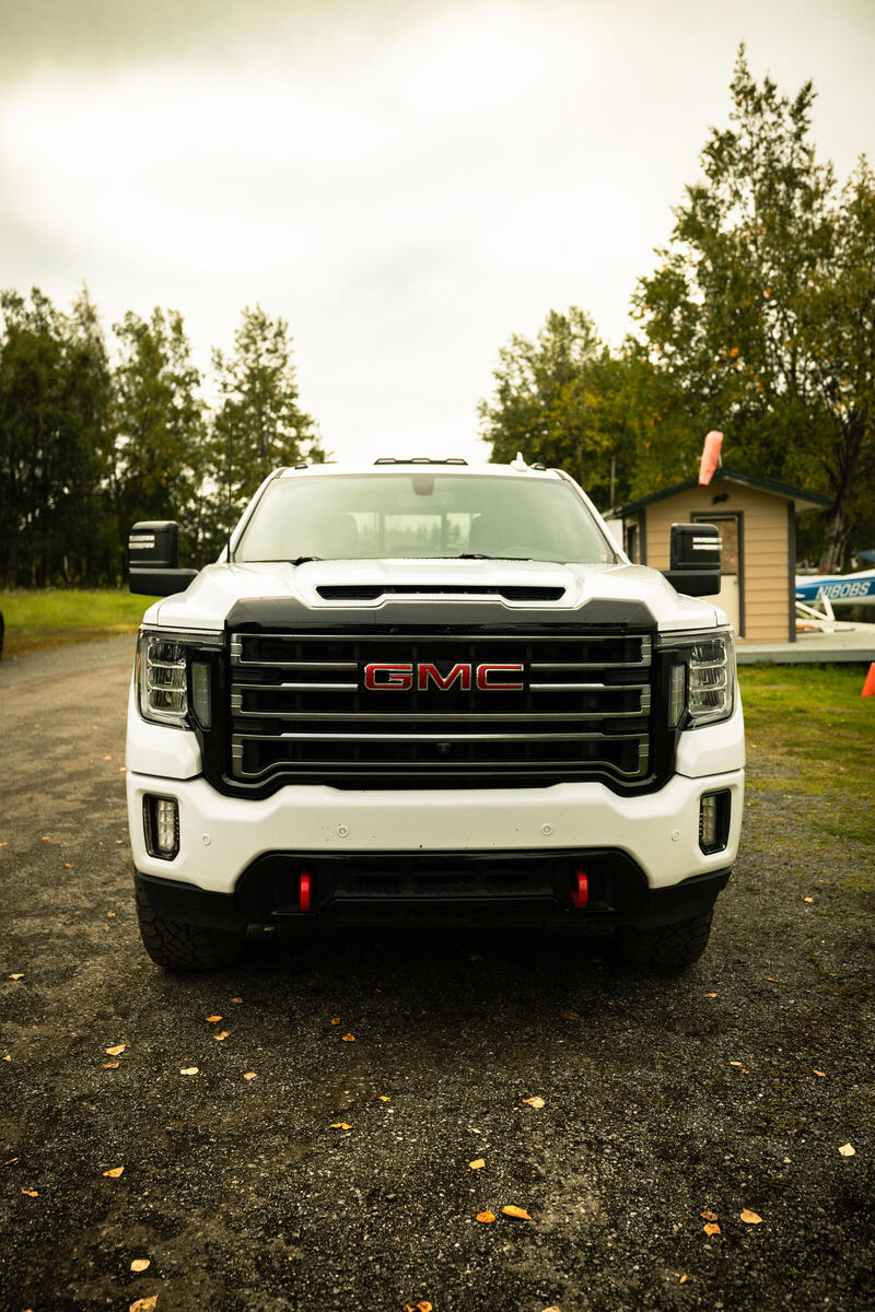 White GMC Sierra AT4 pickup seen from the front on a gravel lot