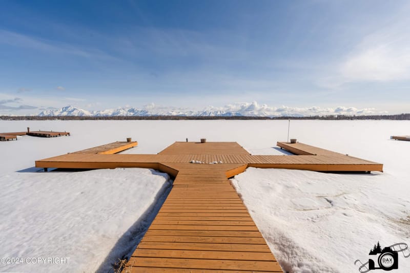 The dock in winter with snow across the frozen lake