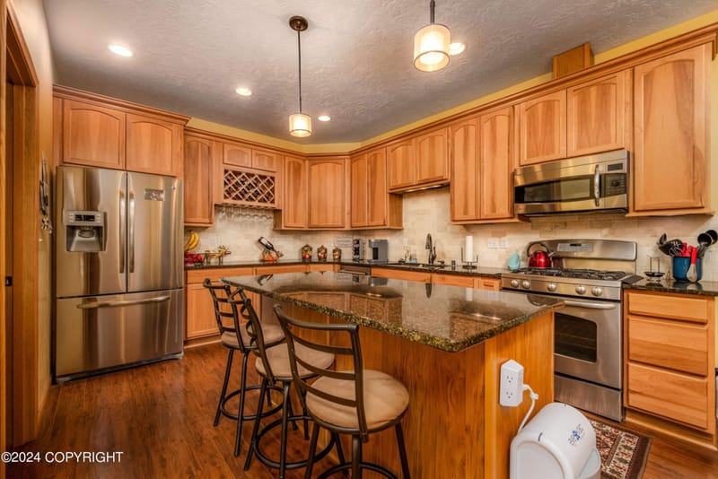 Kitchen with a granite island, wood cabinets and stainless appliances