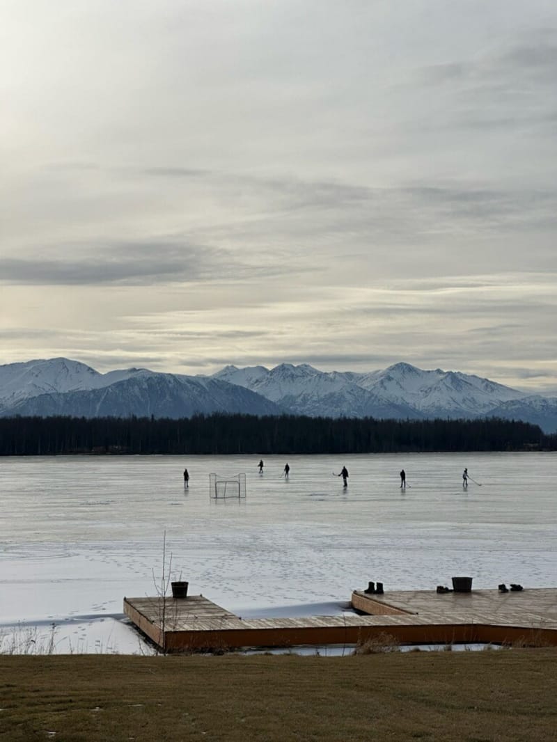 Skaters on the frozen lake, seen from the dock