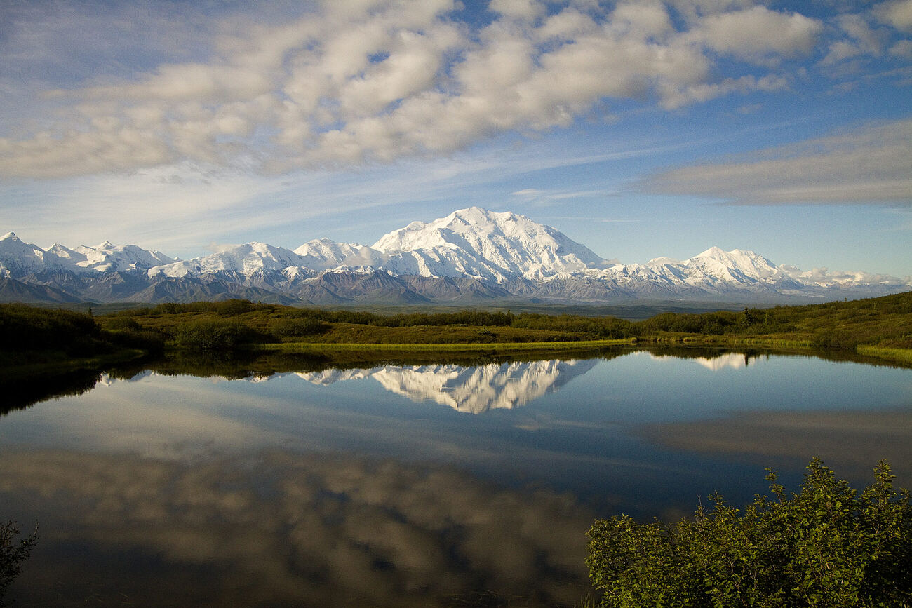 Denali and the Alaska Range reflected in a still pond under a wide sky